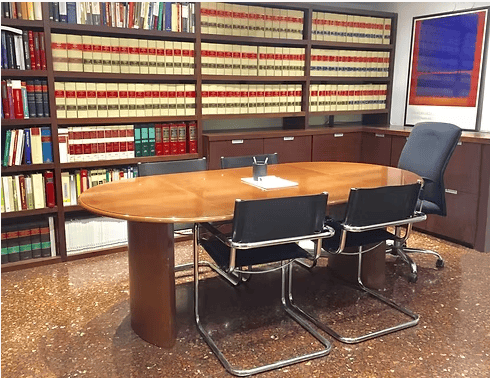 Sala de reuniones del despacho de Finques Canals en Barcelona, con biblioteca jurídica y mesa de reuniones de madera
